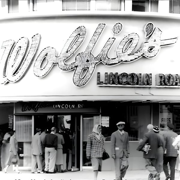Black and white photo of Wolfie's deli with people walking past the entrance on Lincoln Road.