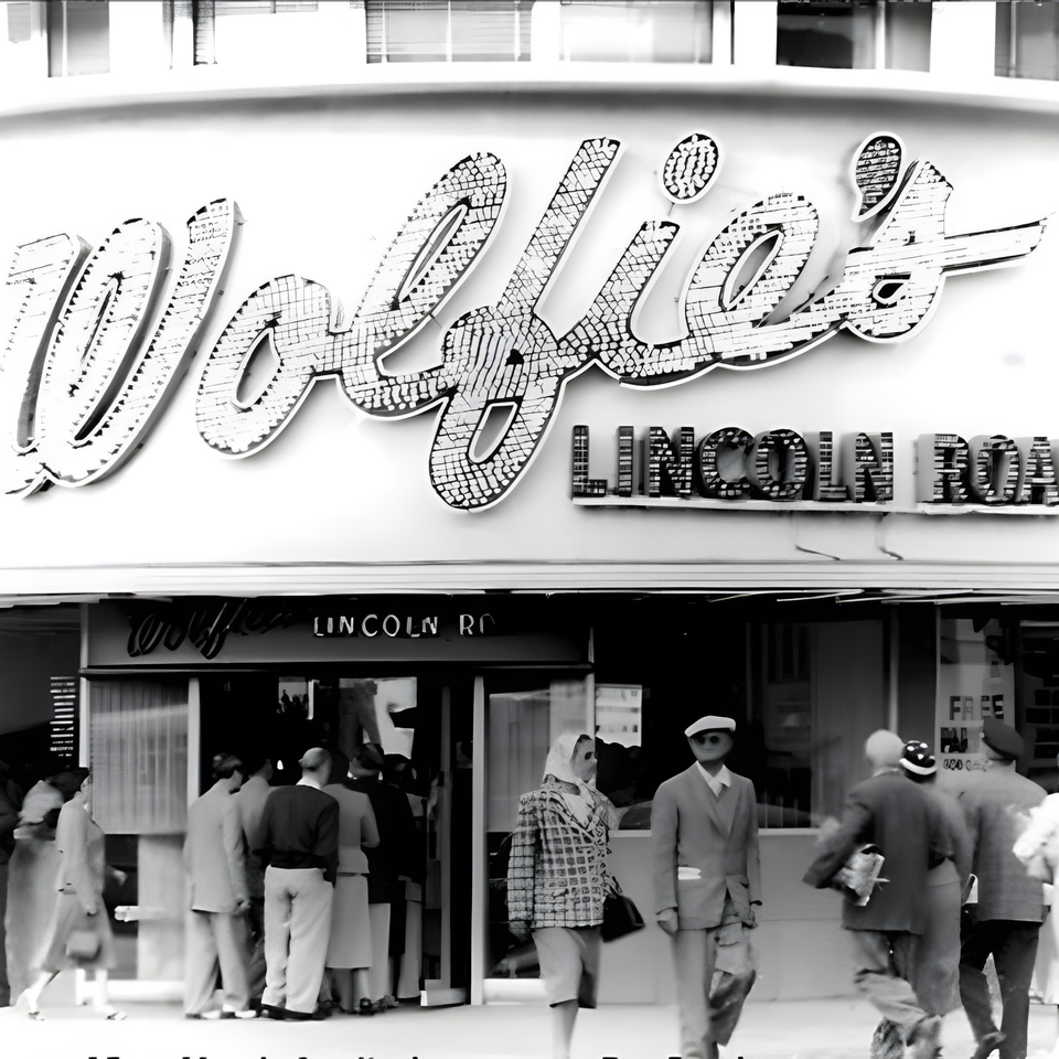 Black and white photo of Wolfie's deli with people walking past the entrance on Lincoln Road.
