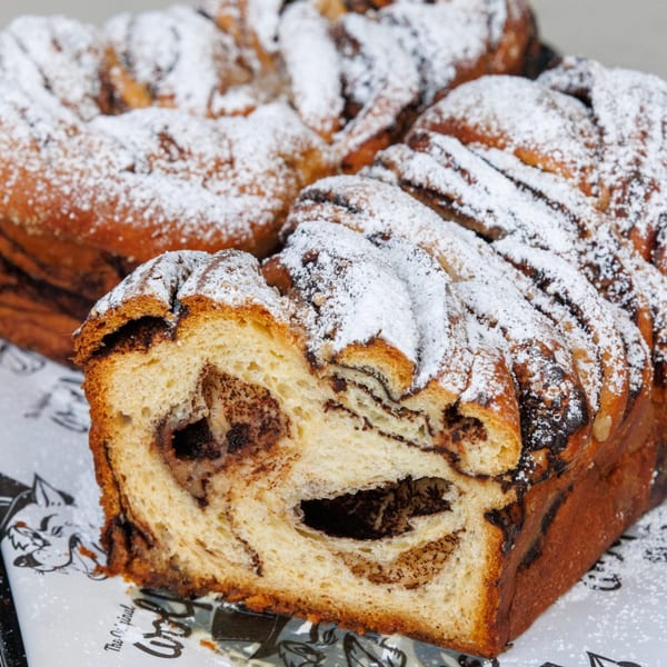 A sliced chocolate babka loaf from The Original Wolfie's, dusted with powdered sugar.